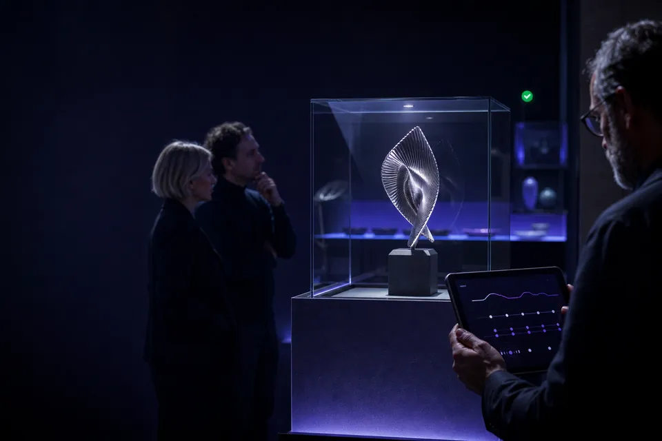 A limited sculptural object displayed in an intimate gallery while a creator monitors its auction.